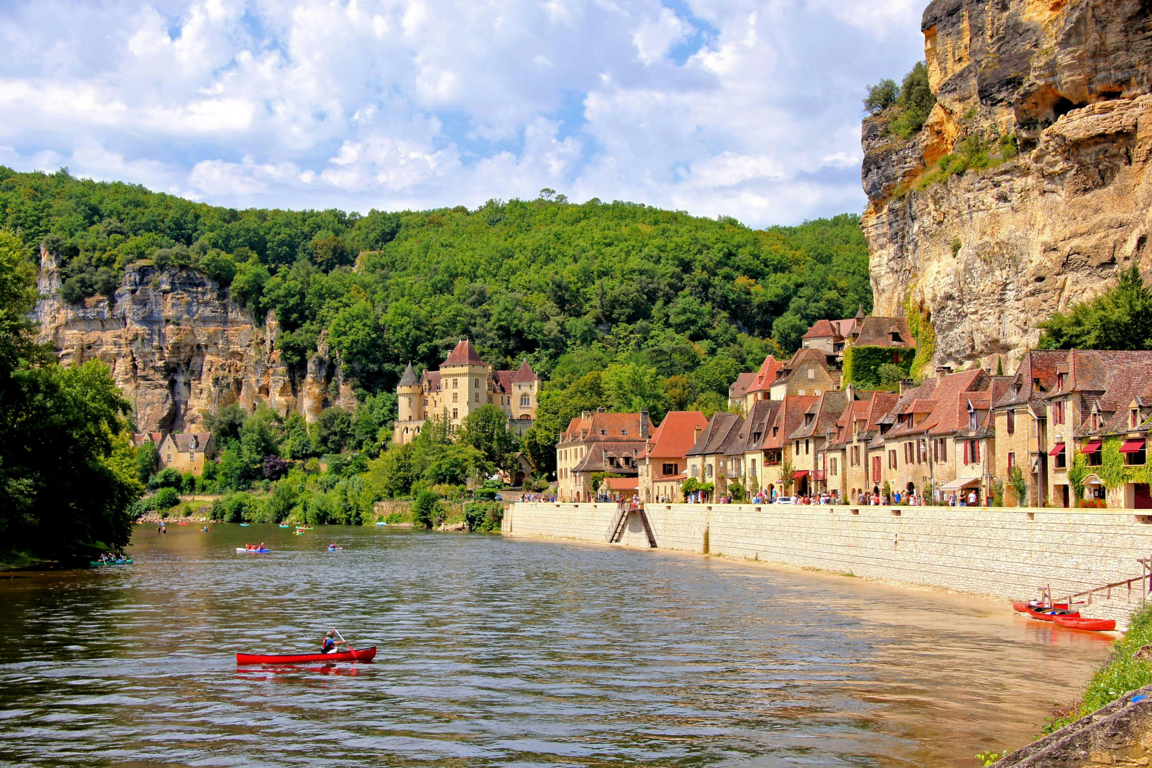 canoeing-dordogne_SEM-Resort-Hero Belle vue du village de La Roque-Gageac sur la rivière Dordogne sur laquelle les touristes font du canoë pendant l'été.