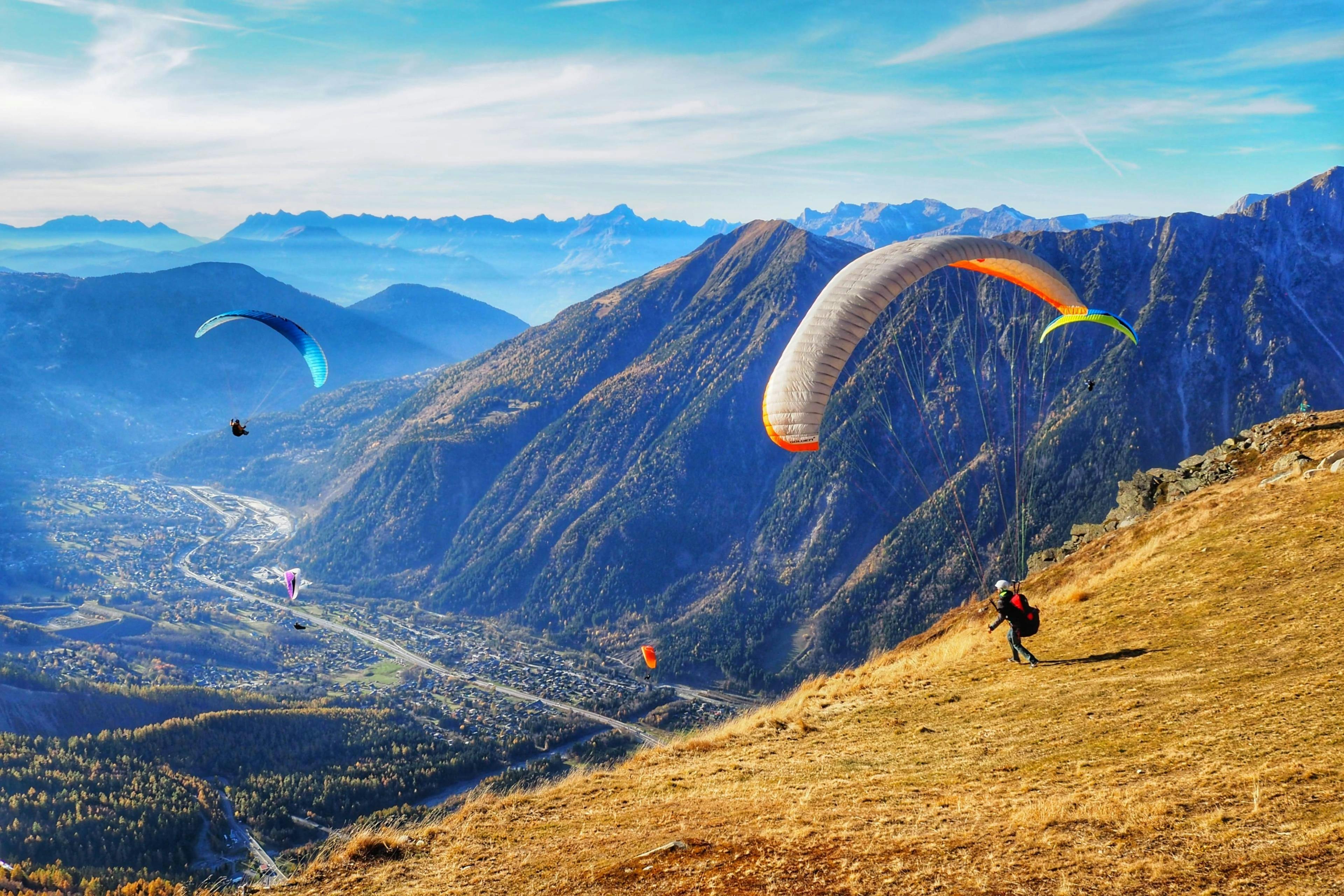 A person is doing a paragliding flight in the Chamonix valley with the snowy mountains in the background.