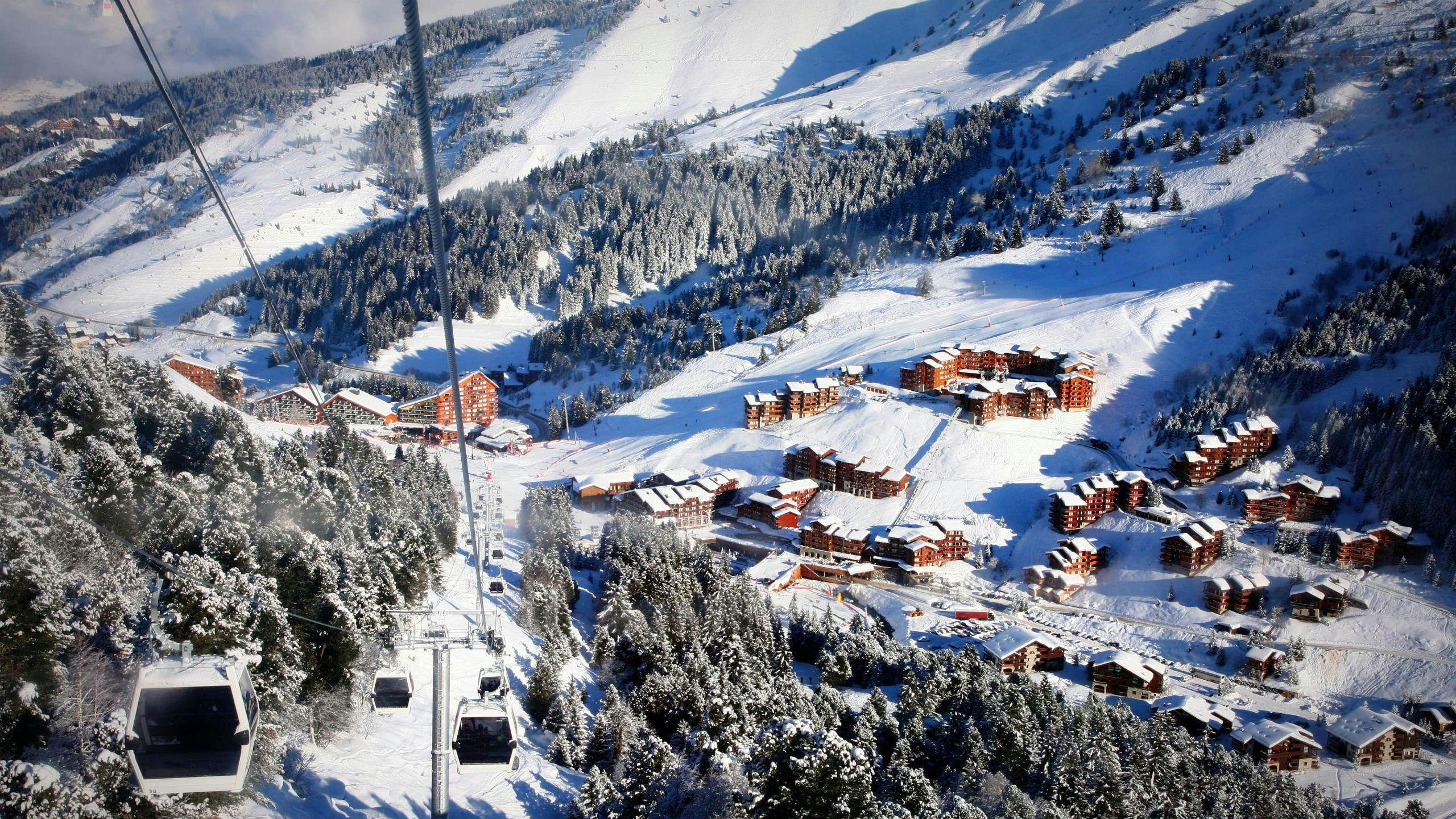 ski-school-meribel_SEM-Resort-Hero A view of the ski resort of Méribel with gondolas ascending one of the mountains where the local ski schools offer a variety of ski lessons.